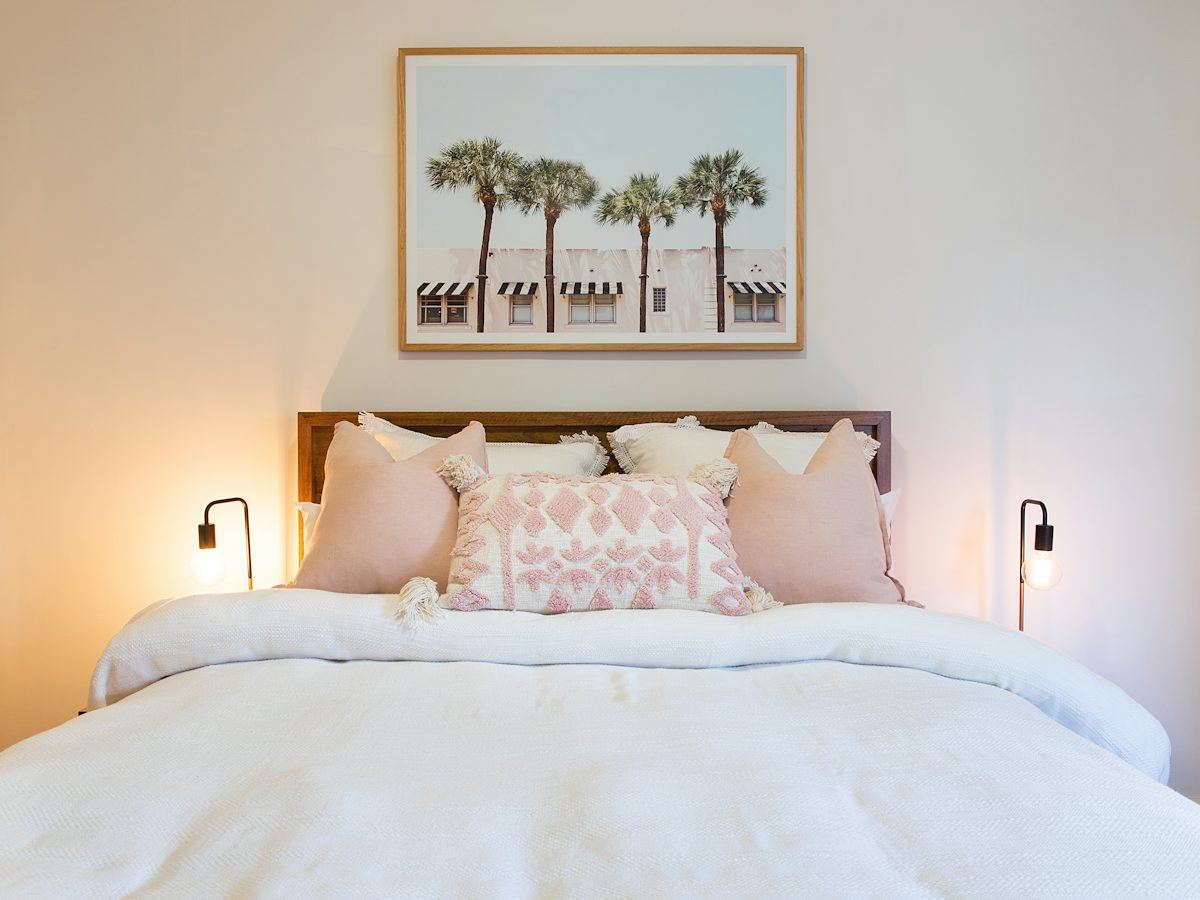 Freshly made white bed with pink cushions, hotel style