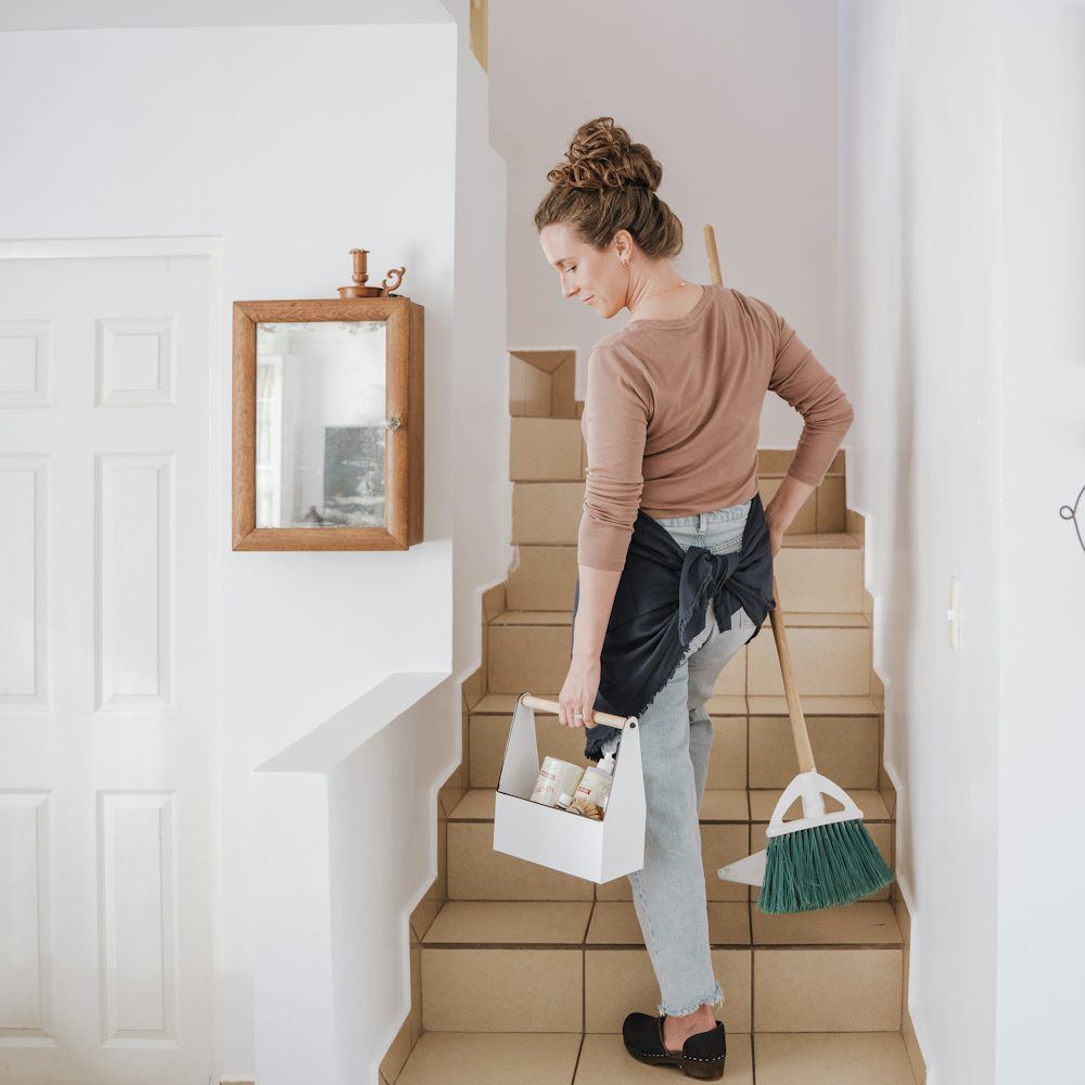 Cleaner carrying a caddy of supplies up the stairs